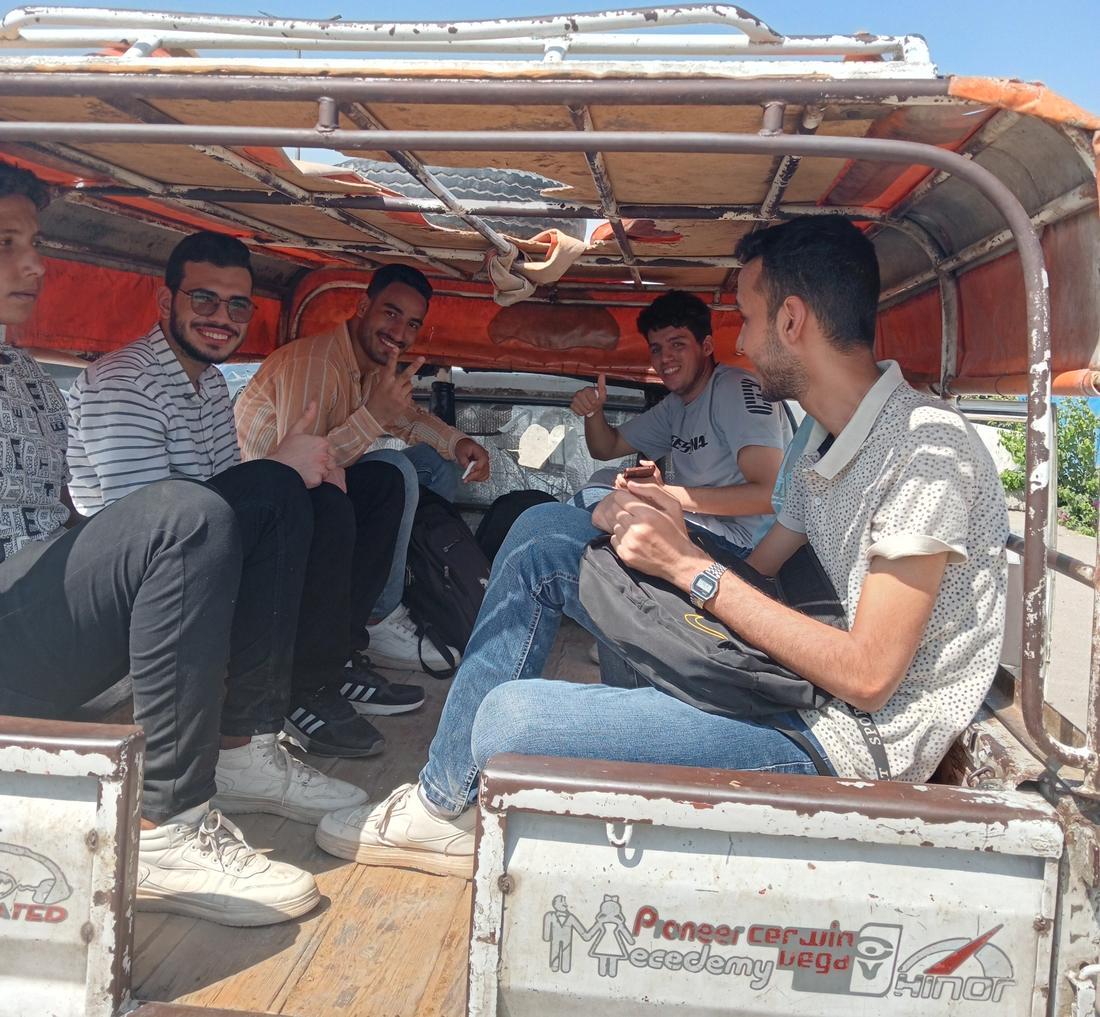 Medical students sitting on benches in the back of a covered pickup truck